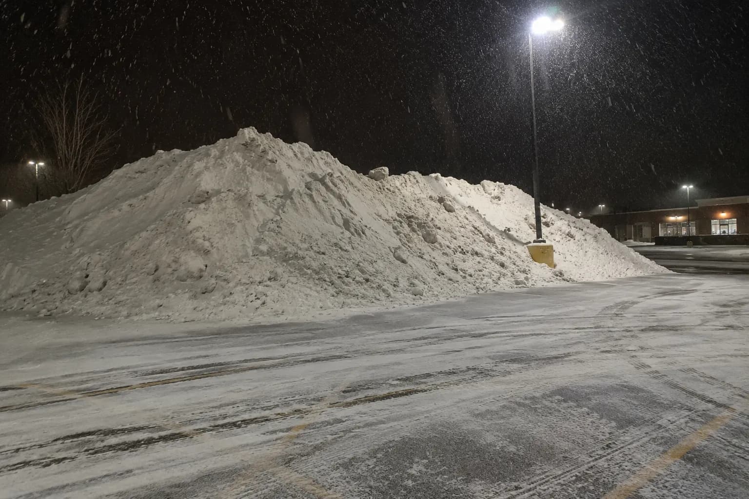 Large plowed snow pile in a commercial parking lot at night in Fond du Lac, Wisconsin
